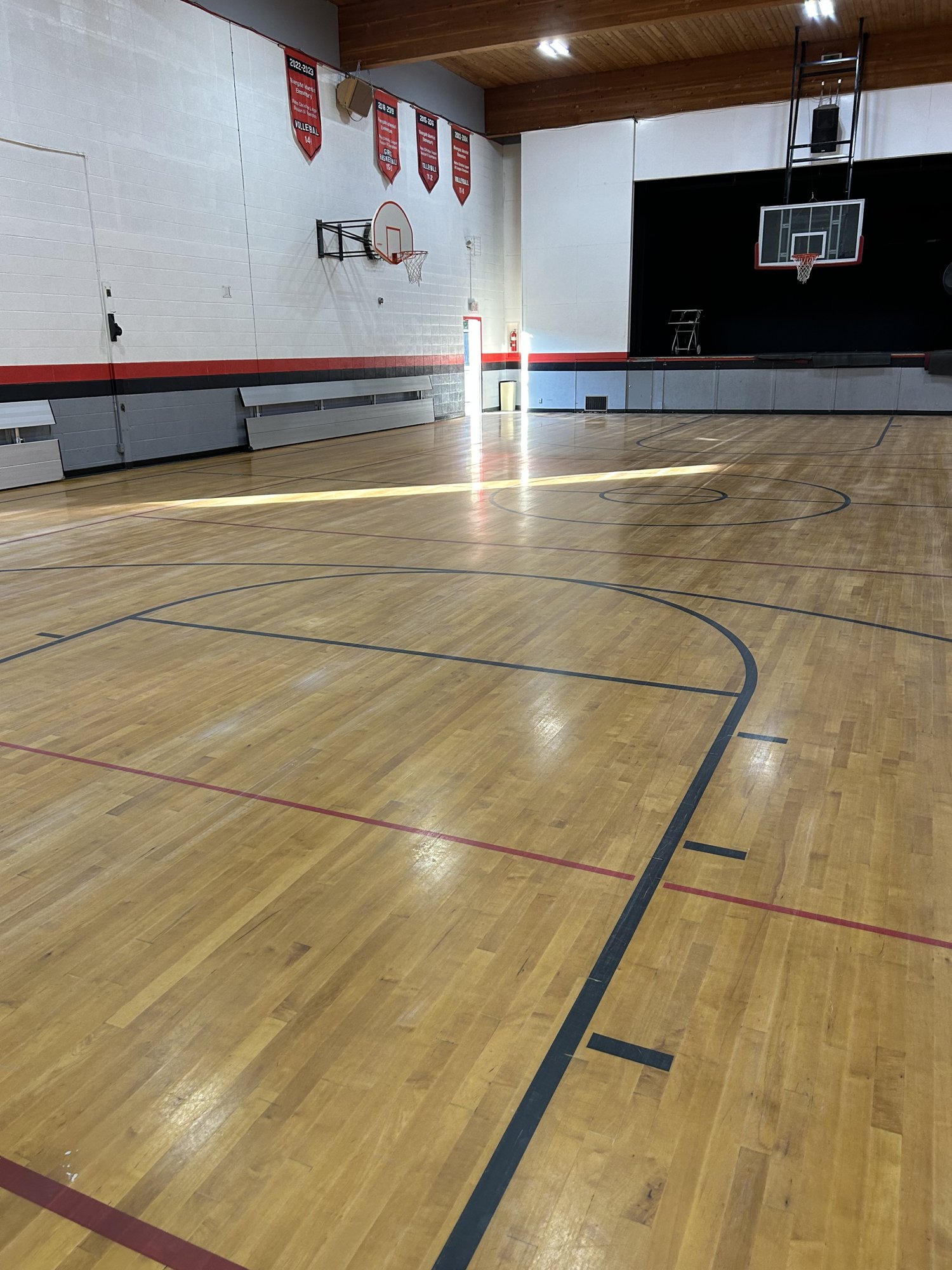 Finished wood gymnasium court with championship banners and basketball hoops