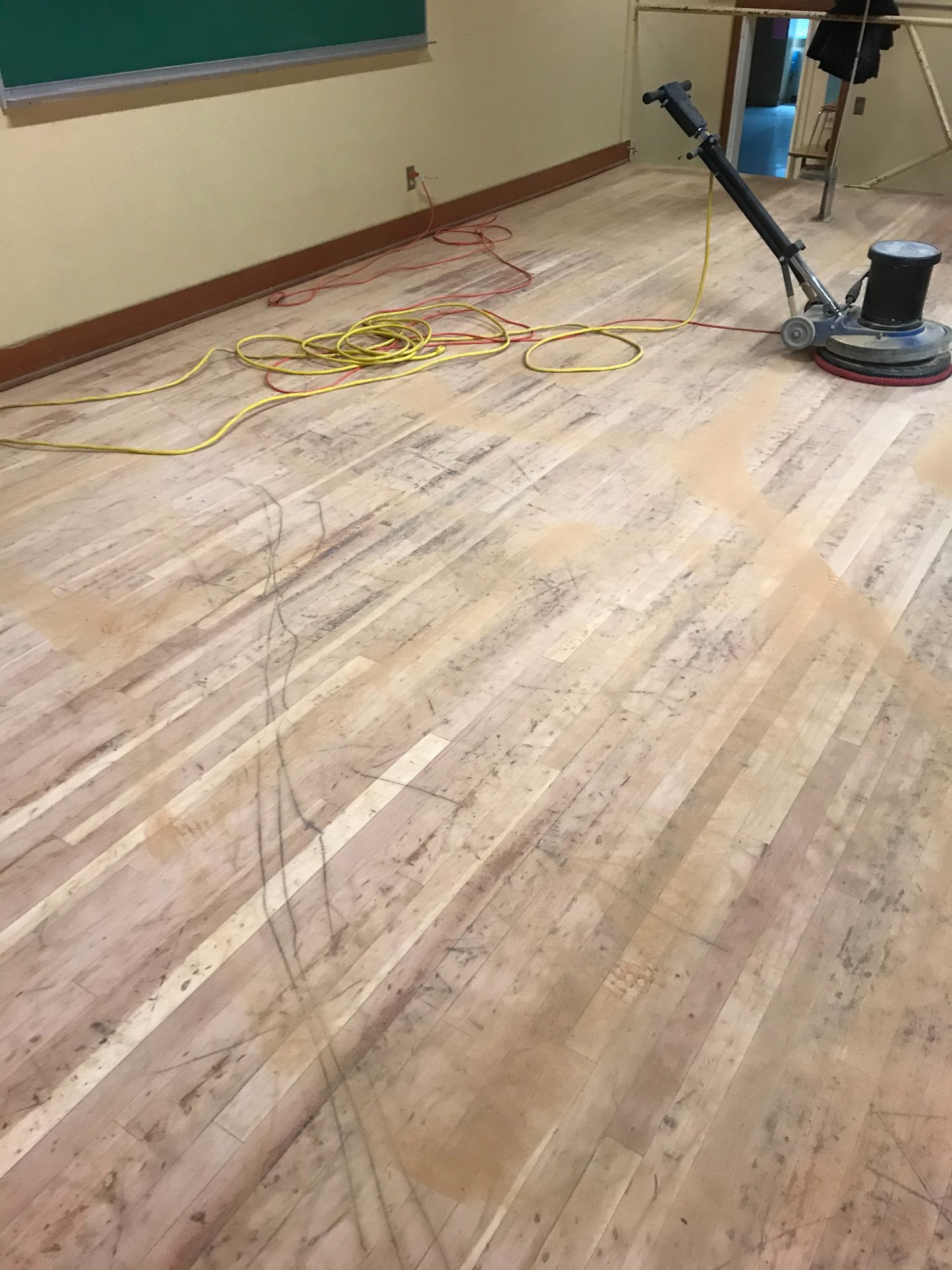 Bare gymnasium wood floor being screened and prepped for refinishing in Portland
